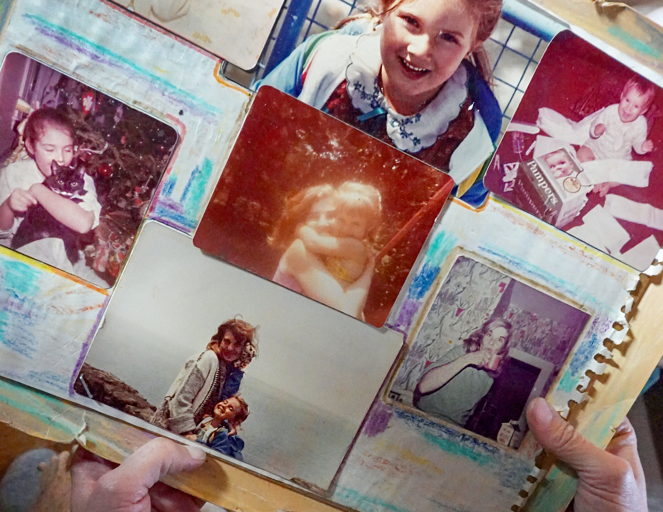 Green holds a thick paper collage with crayon scribbles and six old photos of her with her mother. The central photo is of them embracing tightly when Green was a child. 